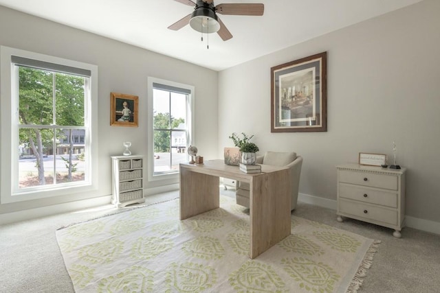 office area featuring light colored carpet, baseboards, ceiling fan, and a wealth of natural light
