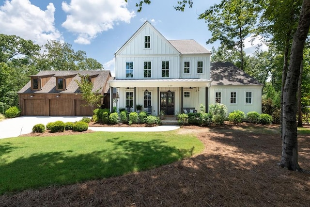 modern farmhouse featuring roof with shingles, board and batten siding, a porch, a front yard, and concrete driveway