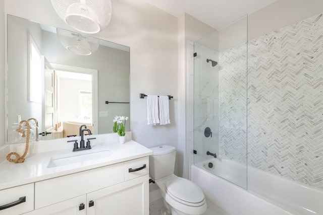 bathroom featuring toilet, combined bath / shower with glass door, and vanity