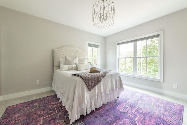 carpeted bedroom featuring baseboards and a chandelier