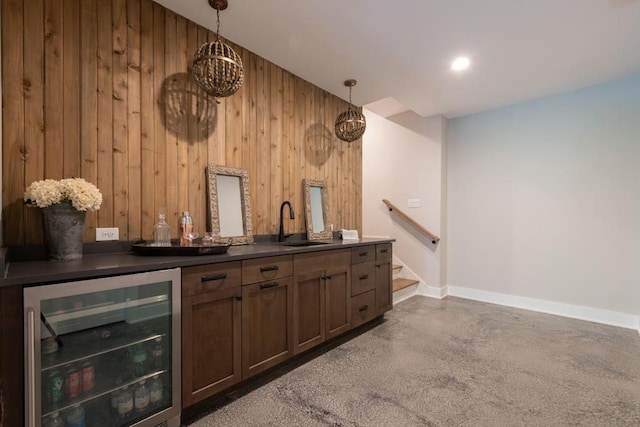 bar with beverage cooler, baseboards, wooden walls, a bar, and decorative light fixtures