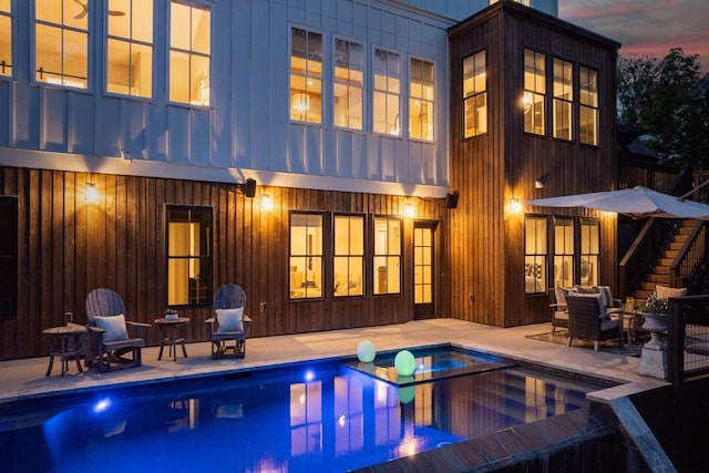 rear view of house featuring a patio, a pool with connected hot tub, and stairway