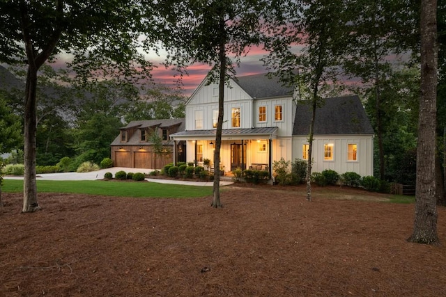 view of front of property featuring board and batten siding, a porch, a standing seam roof, driveway, and metal roof