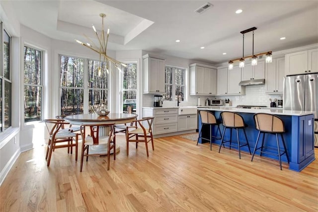 kitchen featuring a breakfast bar area, decorative light fixtures, stainless steel fridge, a tray ceiling, and a kitchen island