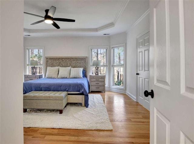 bedroom with wood-type flooring, ornamental molding, a raised ceiling, and ceiling fan