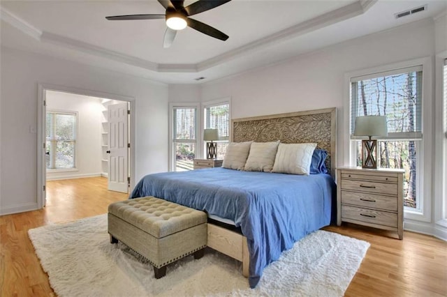 bedroom with a tray ceiling, light hardwood / wood-style flooring, and ornamental molding