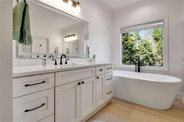 bathroom with hardwood / wood-style flooring, vanity, crown molding, and a bathtub