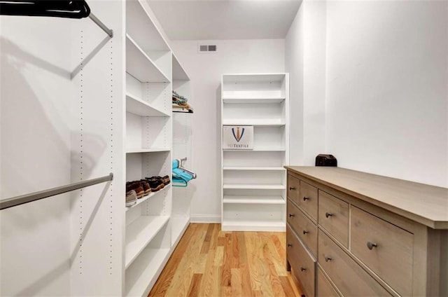 walk in closet with light hardwood / wood-style flooring