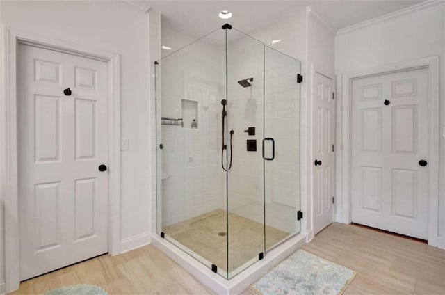 bathroom featuring hardwood / wood-style flooring, ornamental molding, and a shower with shower door