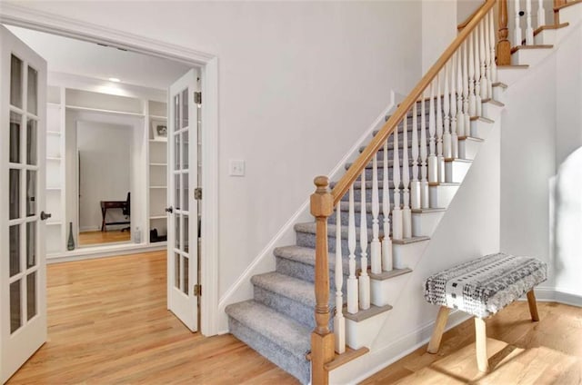 stairway with hardwood / wood-style floors and french doors