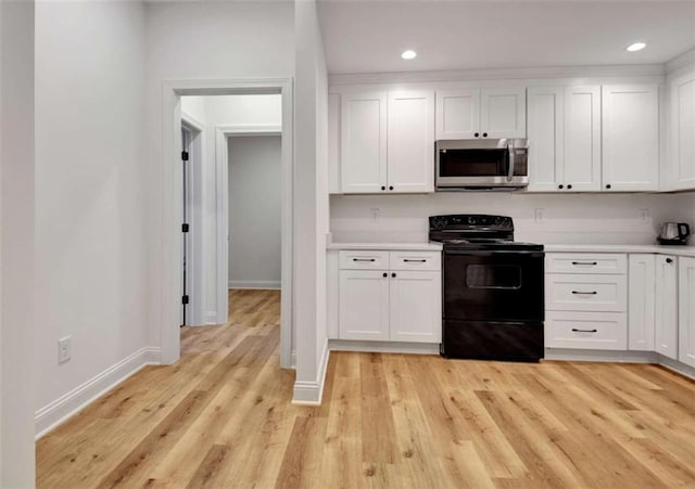 kitchen featuring light hardwood / wood-style floors, black electric range, and white cabinets