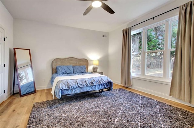 bedroom featuring ceiling fan, multiple windows, and light wood-type flooring