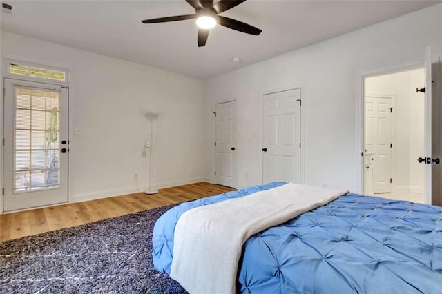 bedroom featuring ceiling fan, hardwood / wood-style flooring, and multiple closets