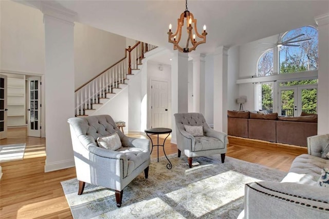 living room with a towering ceiling, light wood-type flooring, and french doors