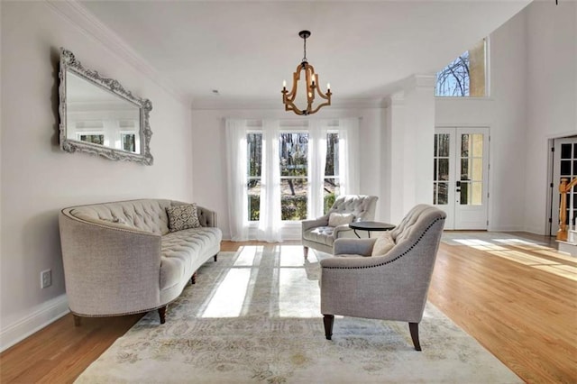 living area with an inviting chandelier, crown molding, hardwood / wood-style floors, and french doors