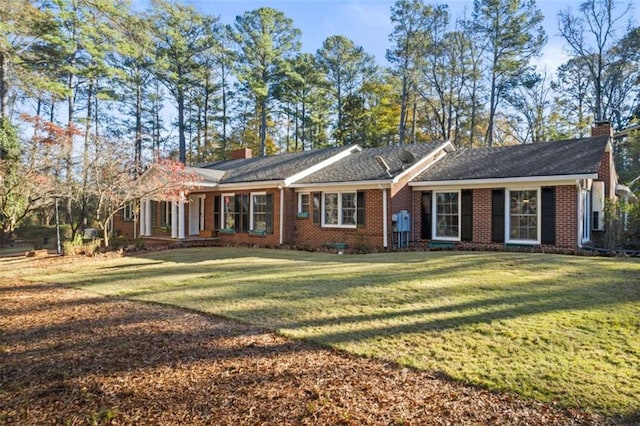 single story home featuring a chimney, a front lawn, and brick siding