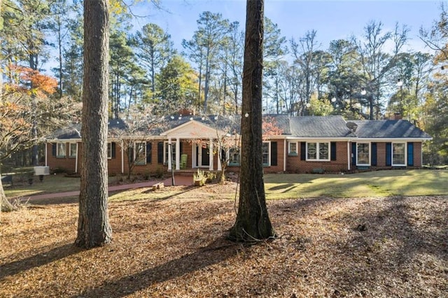 ranch-style house featuring brick siding, a front lawn, and a chimney