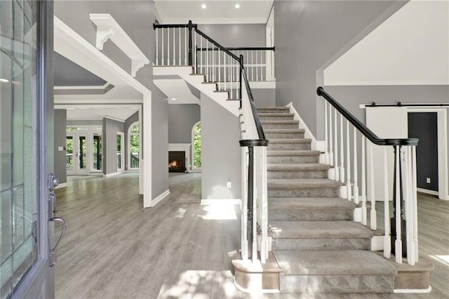 4955 Day Lily Way NW, Acworth, GA 30102 - stairway featuring wood finished floors, a lit fireplace, a high ceiling, ornamental molding, and recessed lighting