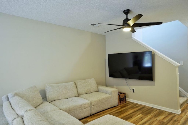 living area with a ceiling fan, visible vents, wood finished floors, baseboards, and stairs