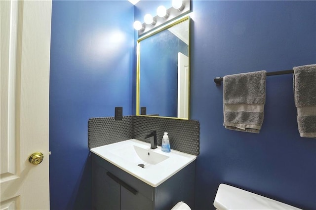 half bathroom featuring vanity, tasteful backsplash, and toilet