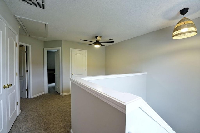 corridor with visible vents, baseboards, attic access, carpet flooring, and an upstairs landing