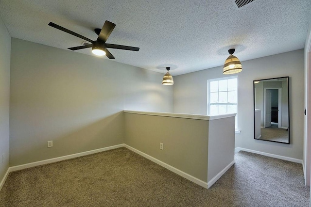 carpeted spare room featuring baseboards, a ceiling fan, and a textured ceiling
