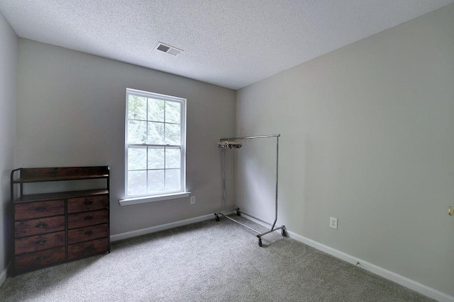 empty room featuring baseboards, carpet flooring, a textured ceiling, and visible vents