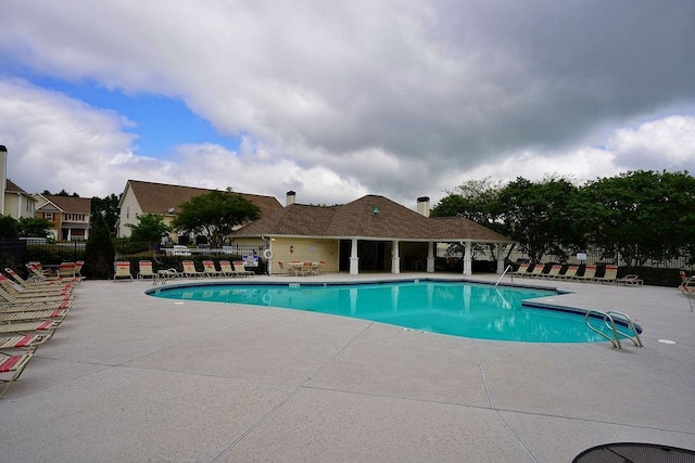 pool featuring fence and a patio