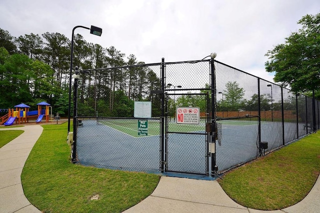 view of property's community with fence, playground community, a gate, a tennis court, and a yard