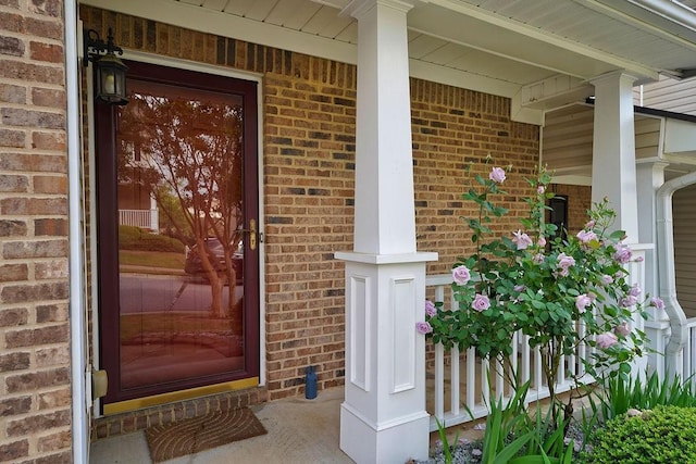 doorway to property featuring brick siding and covered porch