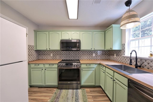 kitchen featuring a sink, green cabinetry, a healthy amount of sunlight, and stainless steel appliances