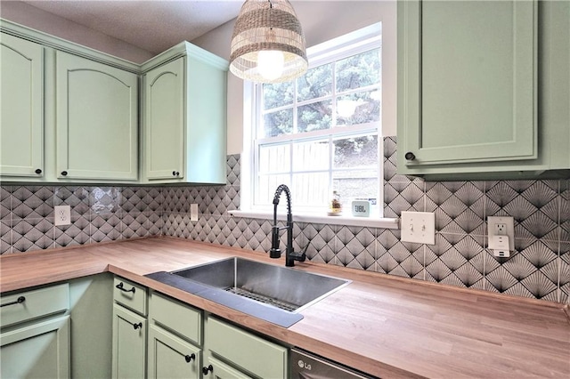 kitchen featuring a sink, tasteful backsplash, green cabinets, and butcher block counters