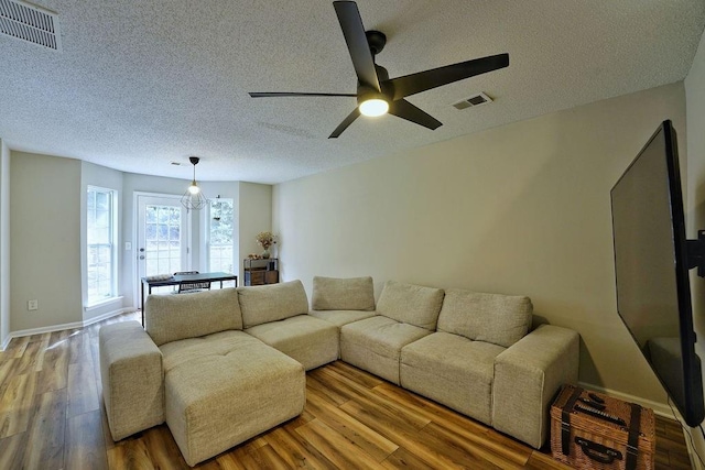 living area featuring a ceiling fan, a textured ceiling, and visible vents