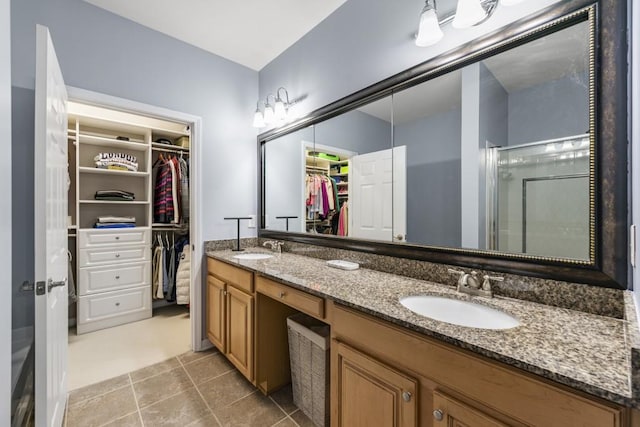 bathroom with double vanity, a spacious closet, a stall shower, and a sink