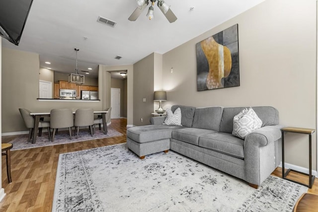 living area with visible vents, ceiling fan, baseboards, and light wood-style floors