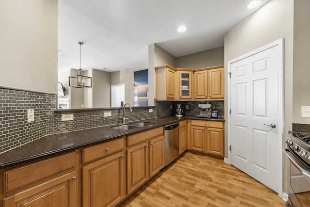 kitchen with light wood-style flooring, a sink, glass insert cabinets, appliances with stainless steel finishes, and decorative backsplash