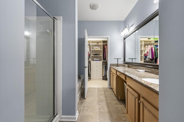 full bath featuring double vanity, a shower stall, a spacious closet, and a sink