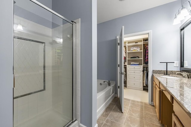 bathroom featuring tile patterned flooring, a walk in closet, a stall shower, a bath, and vanity