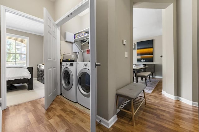 washroom with crown molding, baseboards, laundry area, wood finished floors, and washer and dryer