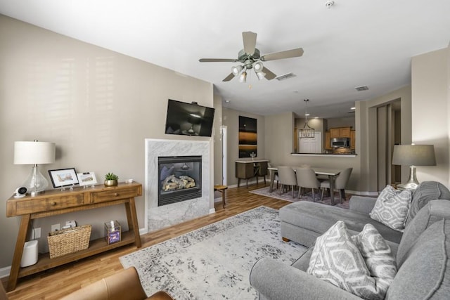 living area featuring light wood finished floors, visible vents, a fireplace, and baseboards