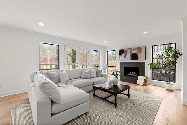 living room with baseboards, a fireplace, recessed lighting, light wood-style floors, and french doors