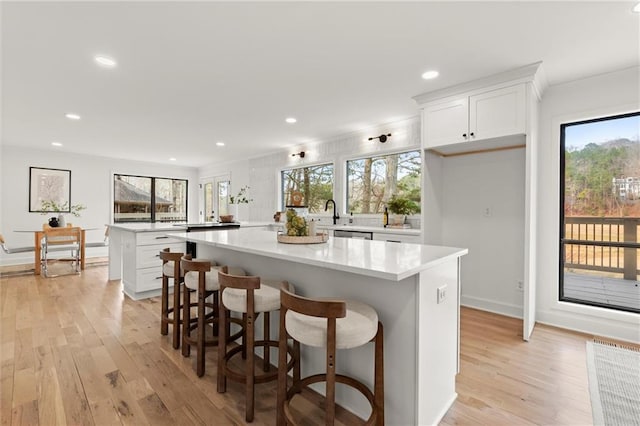 kitchen with a peninsula, light wood-style floors, light countertops, and a kitchen island