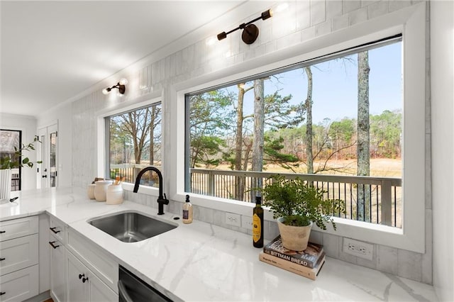 kitchen with a sink, light stone counters, and a wealth of natural light