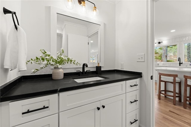 bathroom with vanity, crown molding, and wood finished floors