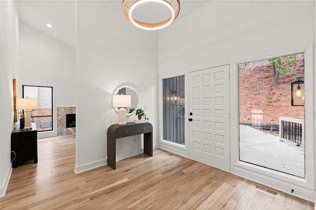 entryway featuring wood finished floors, visible vents, a towering ceiling, and baseboards