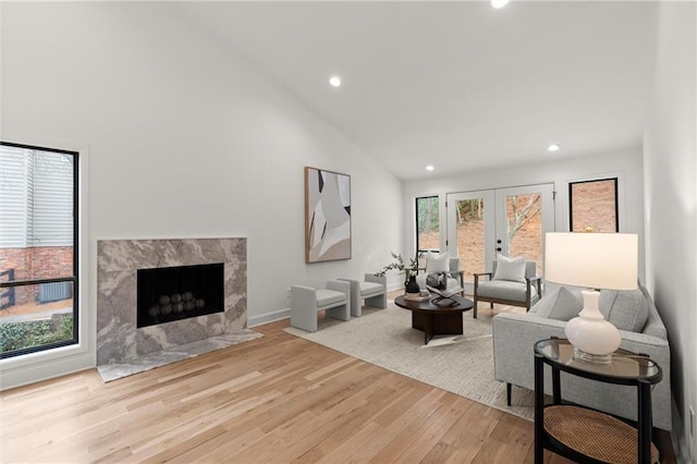 living area featuring high vaulted ceiling, wood finished floors, recessed lighting, french doors, and a fireplace