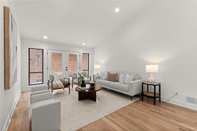 living room featuring visible vents, baseboards, french doors, and light wood finished floors