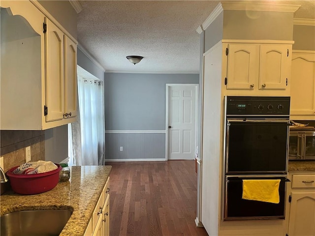 1159 Aurora Ct, Atlanta, GA 30338 - kitchen with dark wood-style flooring, light stone counters, a wainscoted wall, crown molding, and a textured ceiling