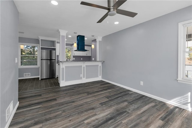 unfurnished living room with sink, dark wood-type flooring, plenty of natural light, and ceiling fan