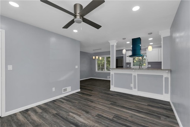 unfurnished living room with ceiling fan, decorative columns, sink, and dark hardwood / wood-style floors